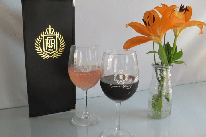 Two glasses of wine, a menu, and orange lilies in a vase.