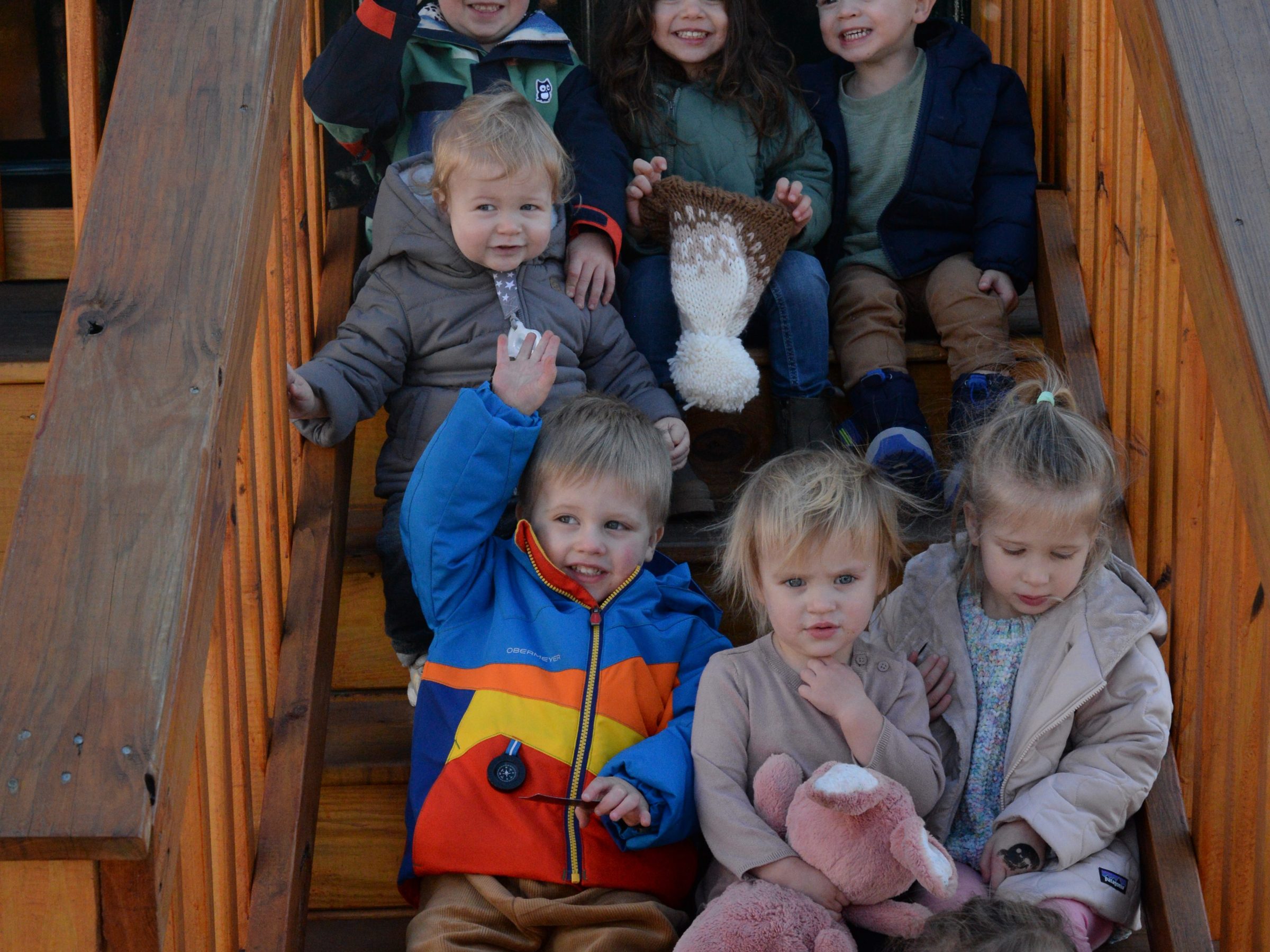 a group of young children sitting next to a teddy bear
