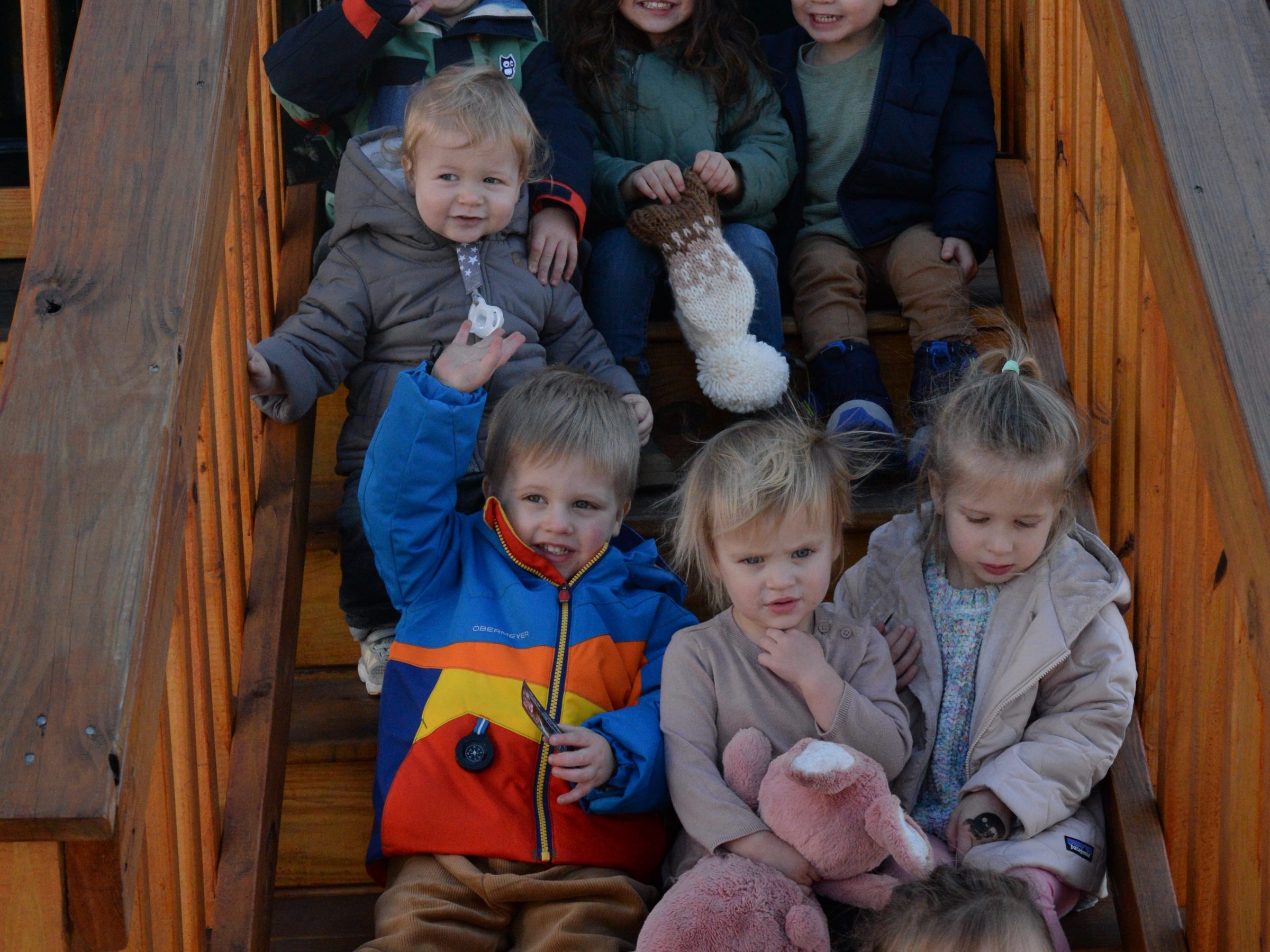 a group of young children sitting next to a stuffed animal