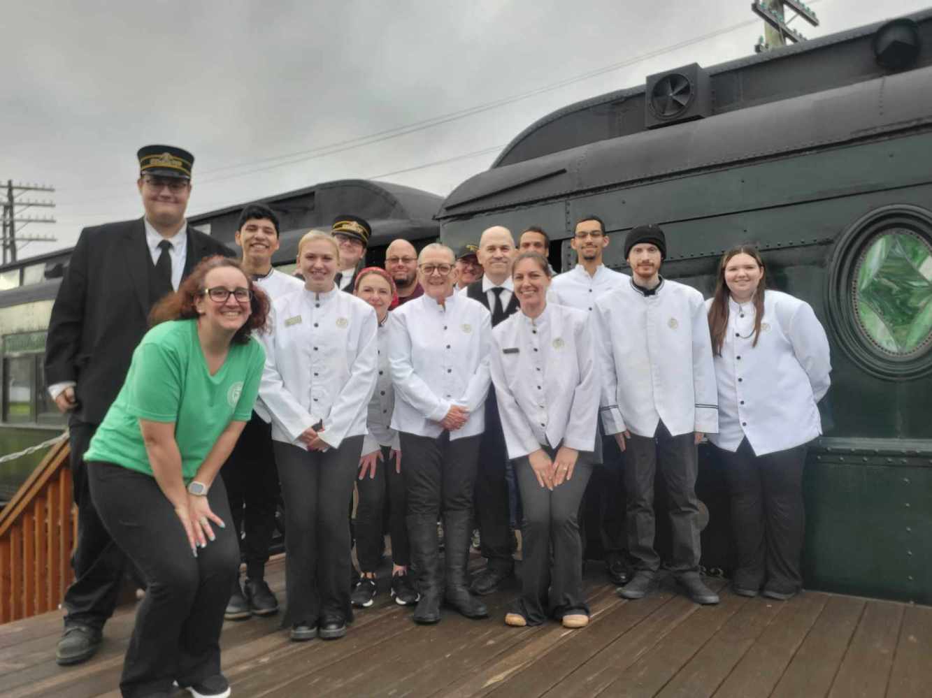 Group of people in uniform posing in front of a vintage train.