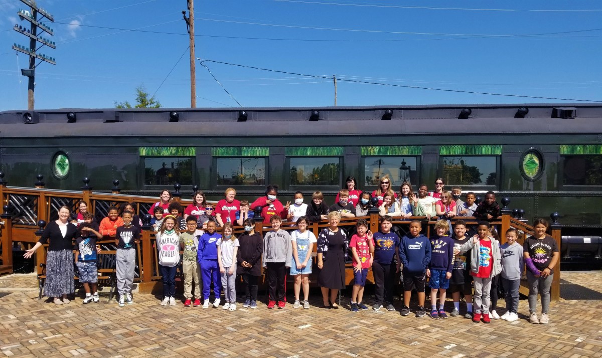 Tompkins VIST Bank EITC Pottstown Field Trip Group of children and adults posing in front of a vintage train car on a sunny day.