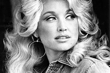 Black and white photo of a woman with long hair and hoop earrings, wearing a denim shirt.